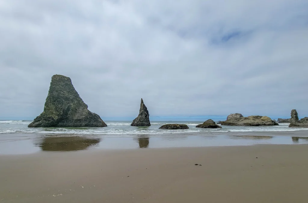 Broad sea stack and a sharp spire standing in the surf at Bandon