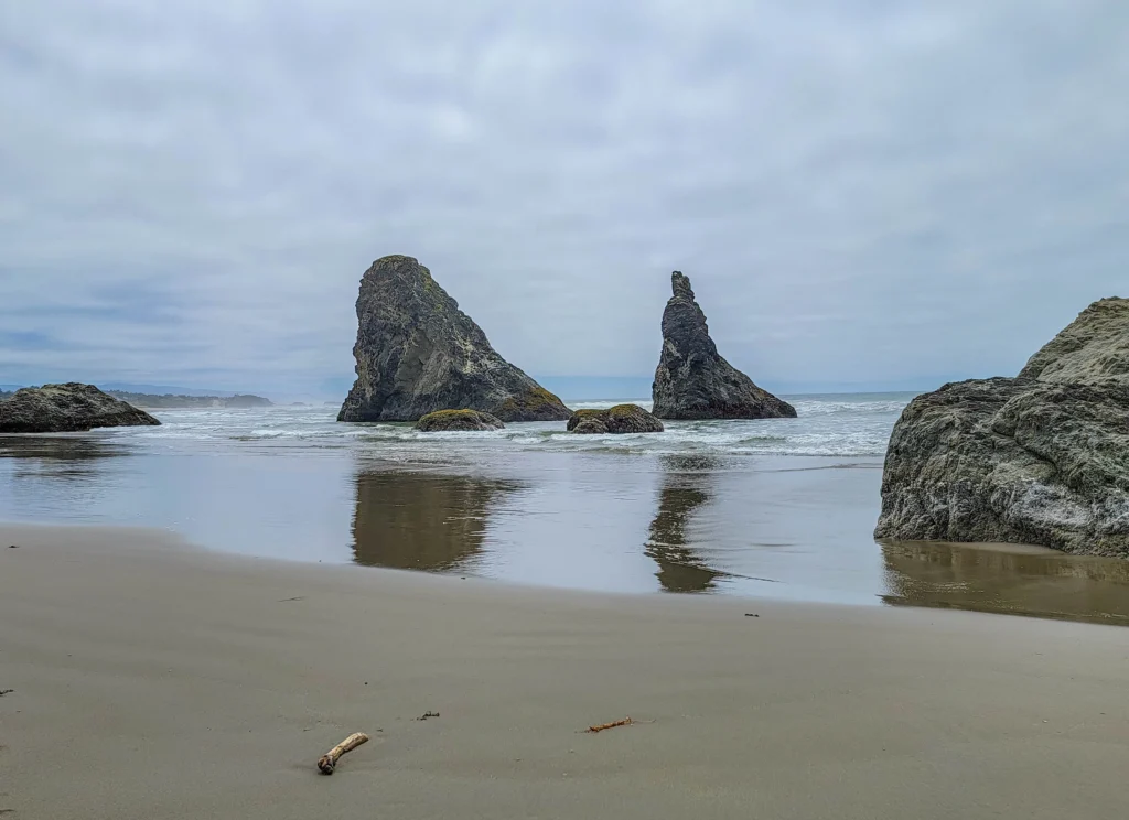 Two sea stacks reflected in wet sand at low tide, Bandon Beach
