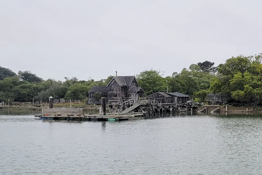 A weathered shingled house standing on pilings above Humboldt Bay