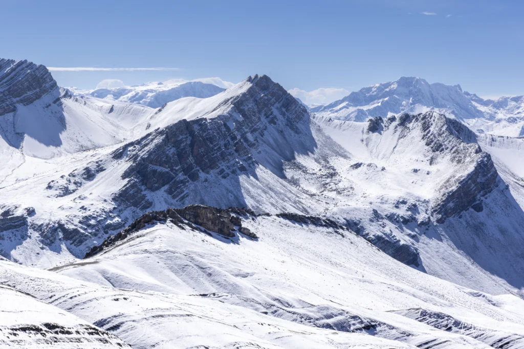 Snow-covered mountain range under a clear blue sky, panoramic alpine scenery in winter